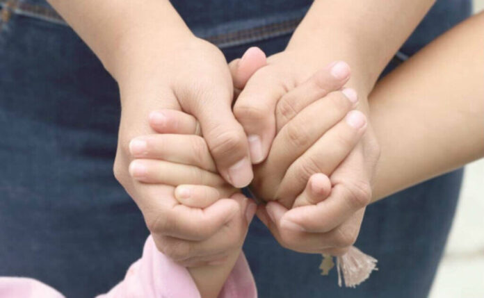 Manos de mujer adulta agarrando las de una niña Manos de mujer adulta agarrando las de una niña